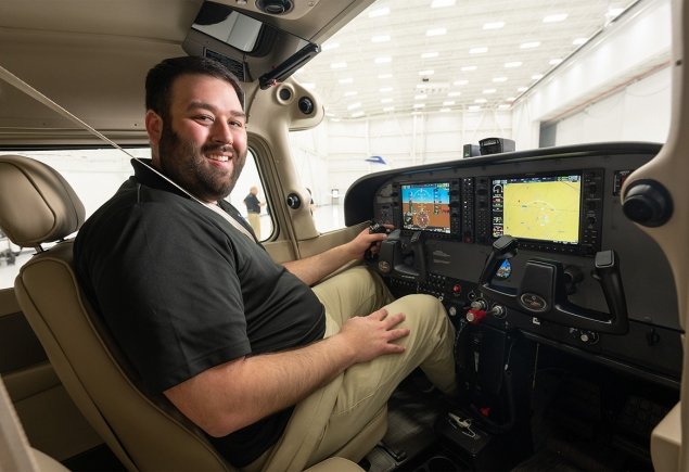 man smiles at camera from across plane