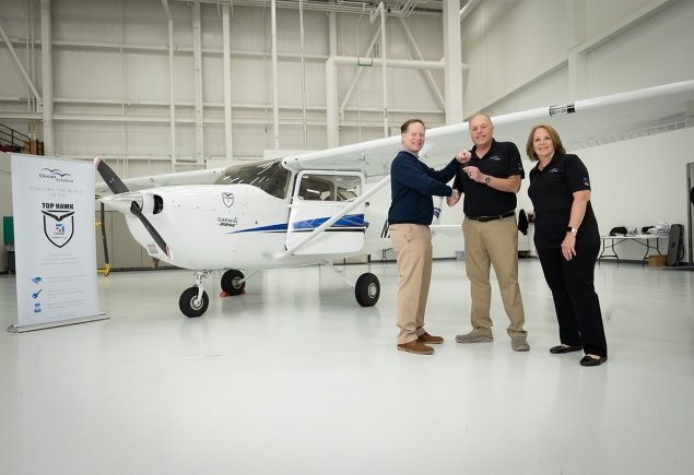 three people standing in front of a plane