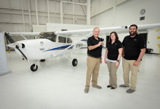 three OA members stand in front of plane