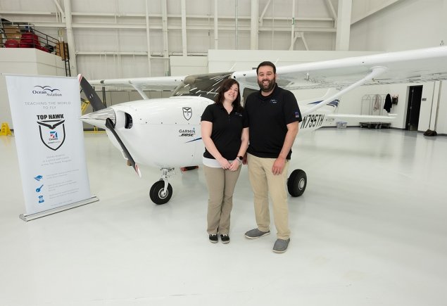 two people stand in front of plane