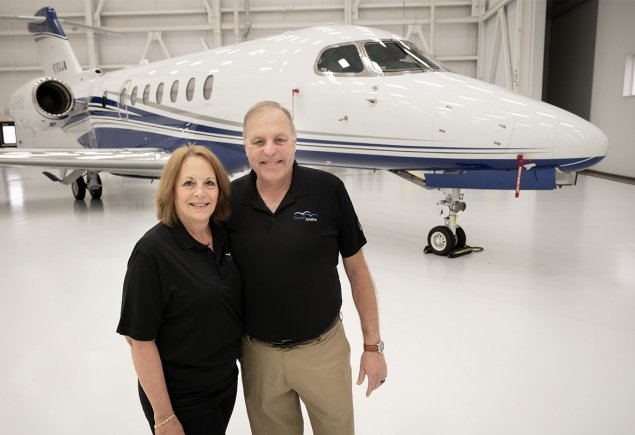 two members stand in front of a plane