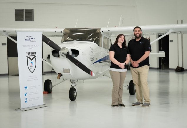 team members stand in front of plane